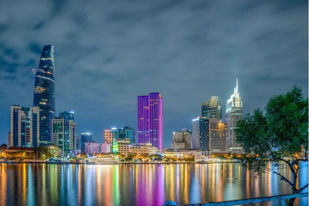 city skyline at night featuring illuminated skyscrapers reflecting on calm water